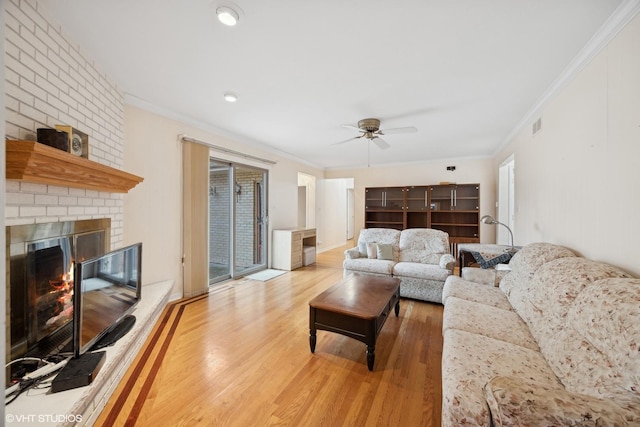 living room with crown molding, a brick fireplace, ceiling fan, plenty of natural light, and wood-type flooring