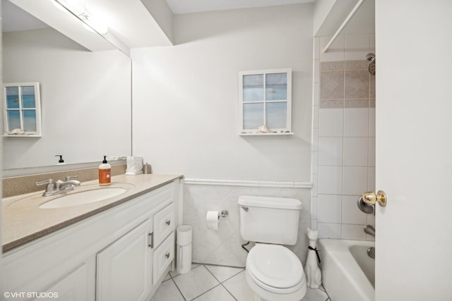 full bathroom with tile patterned floors, toilet, vanity, tile walls, and tiled shower / bath