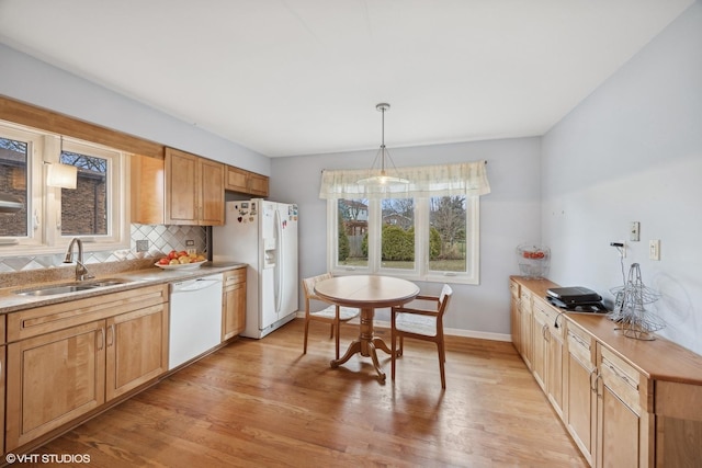 kitchen featuring tasteful backsplash, white appliances, sink, light hardwood / wood-style flooring, and hanging light fixtures