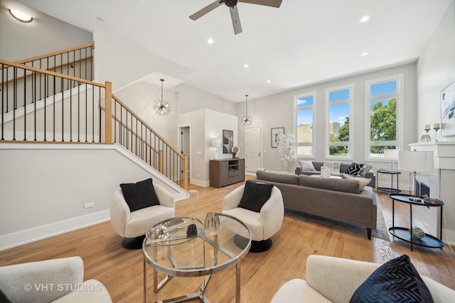 living room with light hardwood / wood-style floors and ceiling fan with notable chandelier