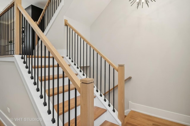 stairs with a chandelier and hardwood / wood-style flooring