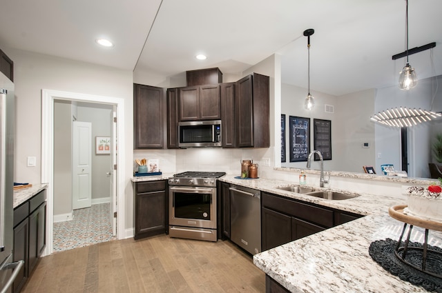 kitchen with sink, hanging light fixtures, light hardwood / wood-style flooring, dark brown cabinets, and stainless steel appliances