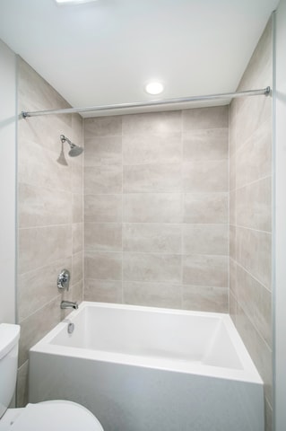 bathroom featuring tiled shower / bath and toilet