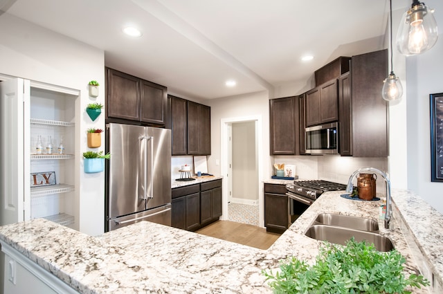 kitchen featuring pendant lighting, light hardwood / wood-style floors, light stone counters, and appliances with stainless steel finishes