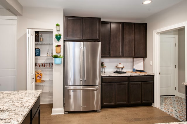 kitchen featuring dark brown cabinets, light wood-type flooring, and stainless steel refrigerator