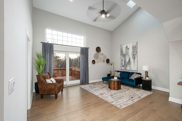 living room with a skylight, ceiling fan, high vaulted ceiling, and hardwood / wood-style flooring