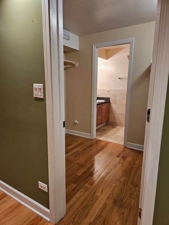 hall with sink, tile walls, and light wood-type flooring