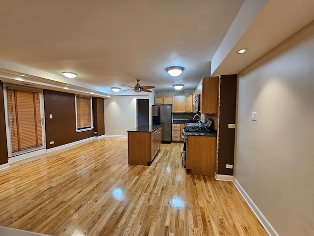 kitchen with a center island, sink, ceiling fan, light hardwood / wood-style floors, and black fridge with ice dispenser