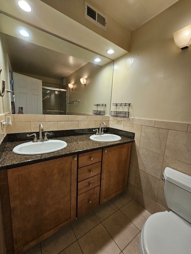 bathroom with an enclosed shower, vanity, tile walls, tile patterned flooring, and toilet