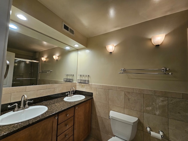 bathroom featuring vanity, toilet, tile walls, and a shower with shower door