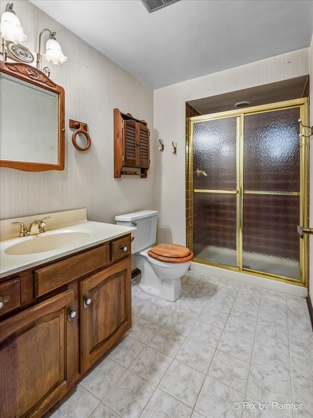 bathroom featuring tile patterned floors, vanity, toilet, and a shower with shower door