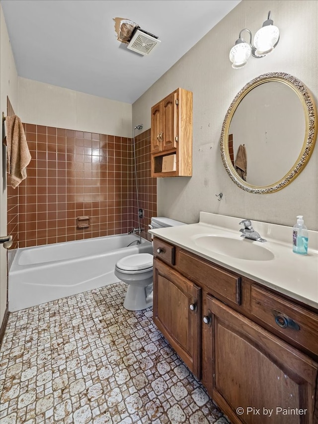 full bathroom featuring tiled shower / bath combo, toilet, and vanity