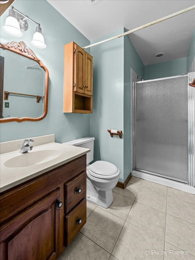 bathroom with tile patterned floors, vanity, a shower with shower door, and toilet