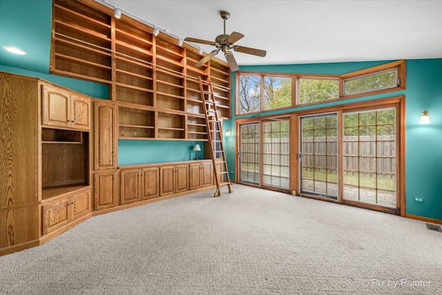 unfurnished living room with carpet, ceiling fan, a healthy amount of sunlight, and vaulted ceiling