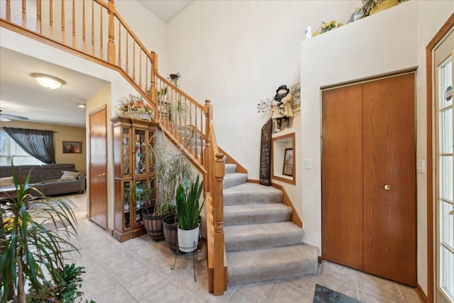 entryway with light tile patterned floors, ceiling fan, and a high ceiling