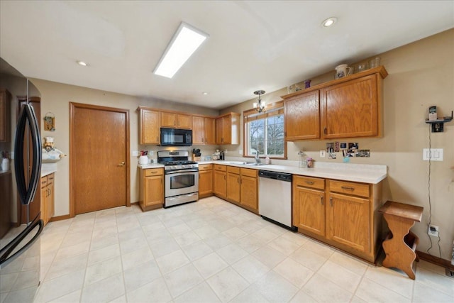 kitchen with appliances with stainless steel finishes, hanging light fixtures, and sink