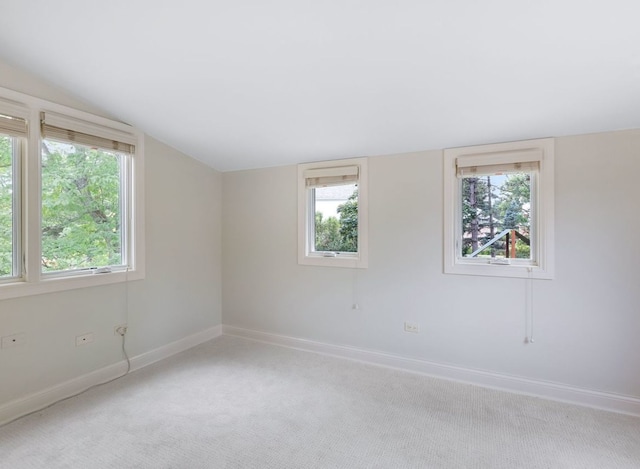 spare room featuring carpet flooring, plenty of natural light, and vaulted ceiling