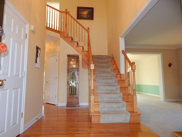 stairway featuring hardwood / wood-style floors, a towering ceiling, and ornamental molding