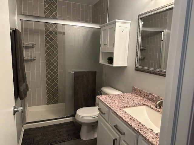 bathroom featuring tile patterned floors, vanity, an enclosed shower, and toilet