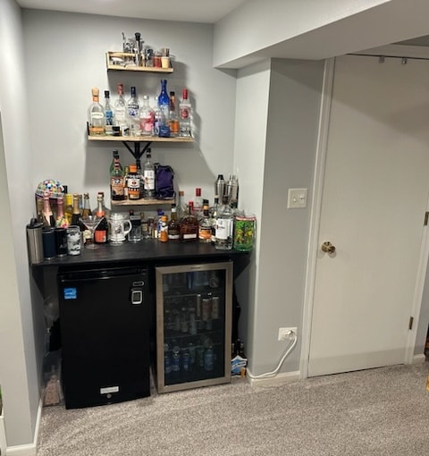 bar featuring black refrigerator, carpet floors, and wine cooler