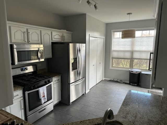 kitchen with dark tile patterned flooring, decorative light fixtures, white cabinetry, and appliances with stainless steel finishes