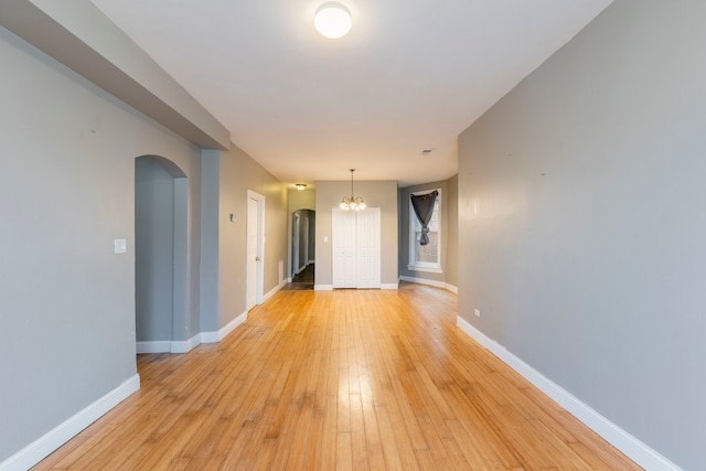 empty room with light hardwood / wood-style flooring and a notable chandelier