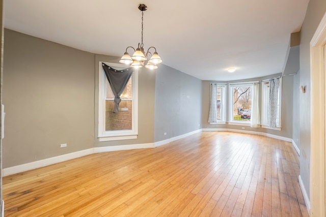 empty room with an inviting chandelier and light hardwood / wood-style flooring