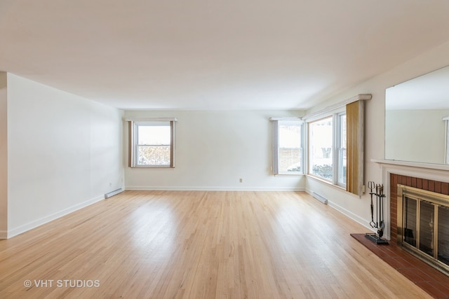 unfurnished living room featuring a brick fireplace, baseboards, and light wood-style floors