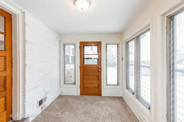 entrance foyer featuring a wealth of natural light, visible vents, brick wall, and carpet