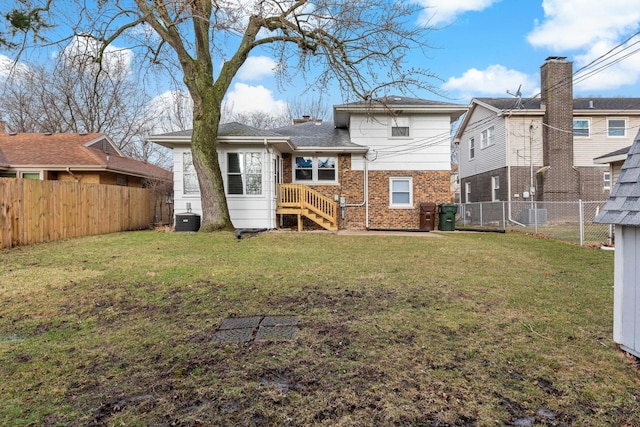 rear view of house featuring central air condition unit, a lawn, brick siding, and a fenced backyard