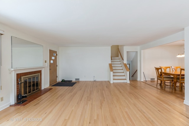 living room with a fireplace, hardwood / wood-style floors, and an inviting chandelier