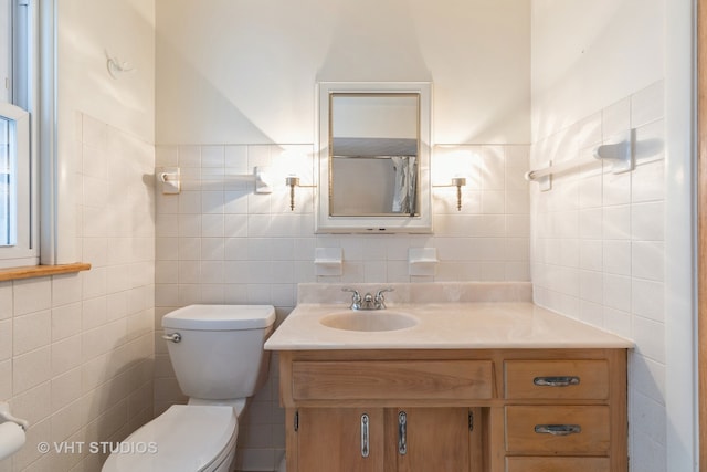 bathroom featuring vanity, toilet, and tile walls