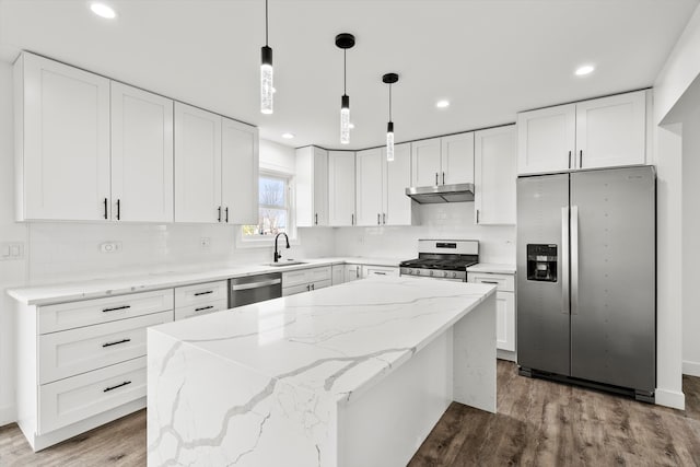 kitchen with white cabinets, decorative light fixtures, stainless steel appliances, and a kitchen island