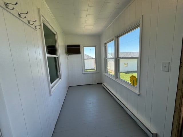 unfurnished sunroom featuring a wall mounted AC and a baseboard radiator