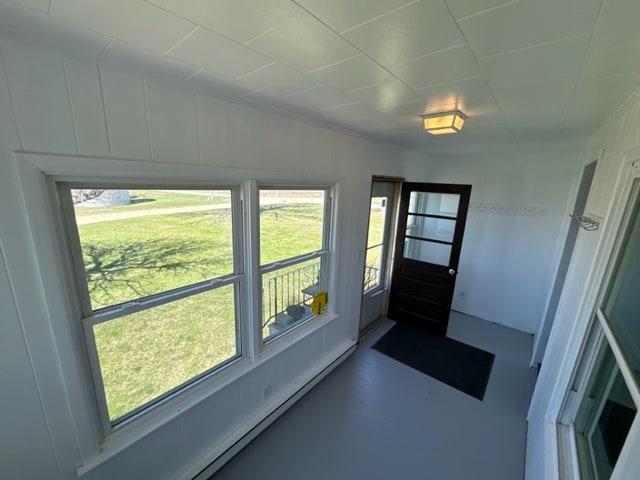 doorway with plenty of natural light, concrete flooring, and baseboard heating