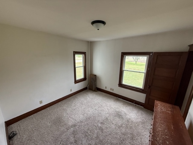 carpeted empty room featuring radiator heating unit