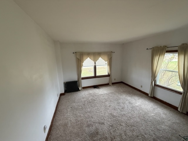 carpeted spare room featuring plenty of natural light and radiator heating unit