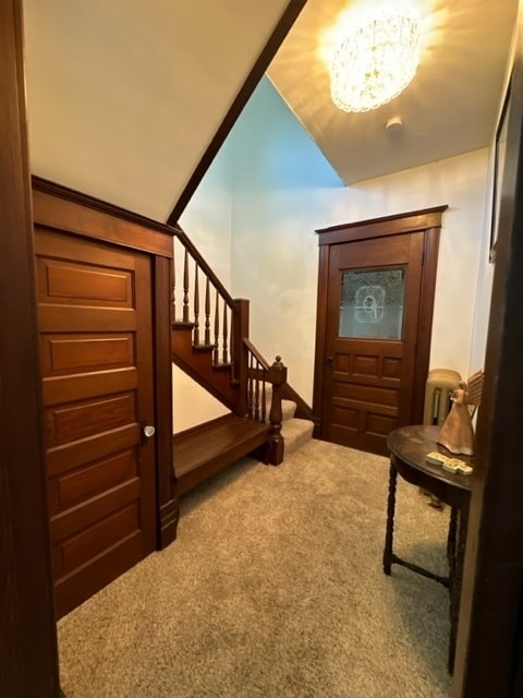 carpeted foyer with lofted ceiling and a notable chandelier