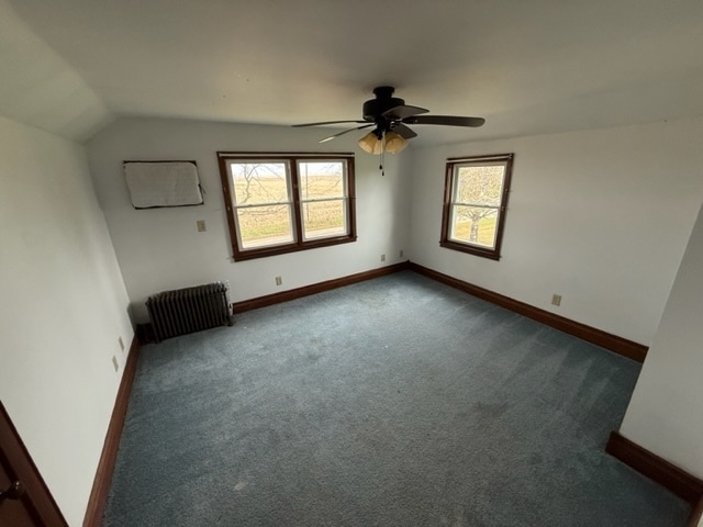 carpeted empty room with ceiling fan, radiator heating unit, and lofted ceiling