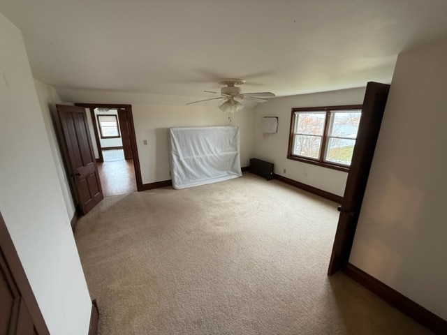 bonus room featuring ceiling fan and light carpet