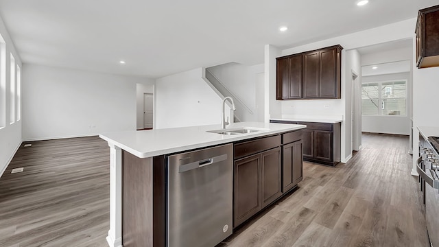 kitchen with dark brown cabinetry, dishwasher, sink, a kitchen island with sink, and light wood-type flooring