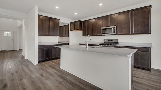 kitchen featuring sink, stainless steel appliances, light hardwood / wood-style flooring, an island with sink, and dark brown cabinets