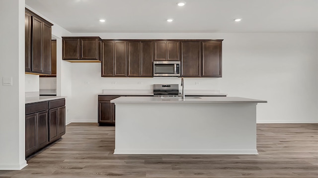 kitchen featuring a center island with sink, light hardwood / wood-style floors, sink, and appliances with stainless steel finishes