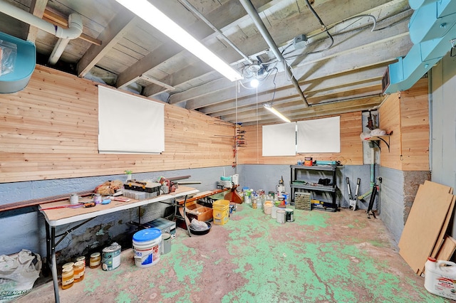 misc room featuring a workshop area, wood walls, and concrete flooring