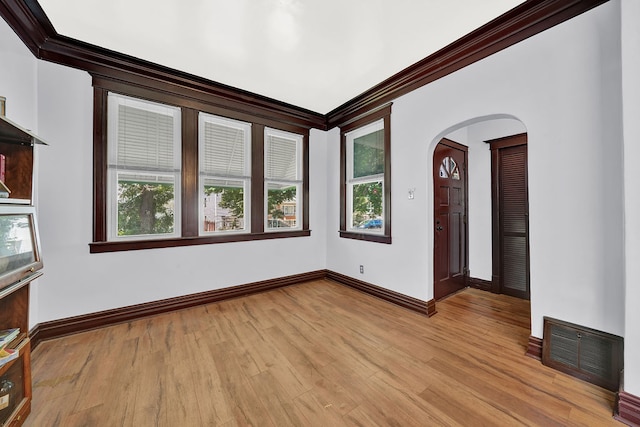 spare room featuring a wealth of natural light, light hardwood / wood-style flooring, and ornamental molding