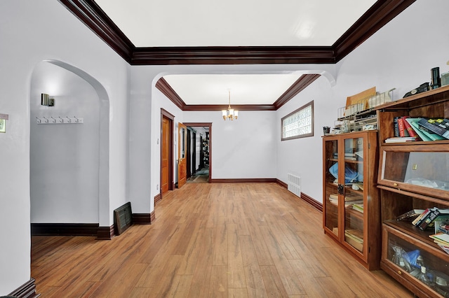 hall featuring a chandelier, light wood-type flooring, and crown molding