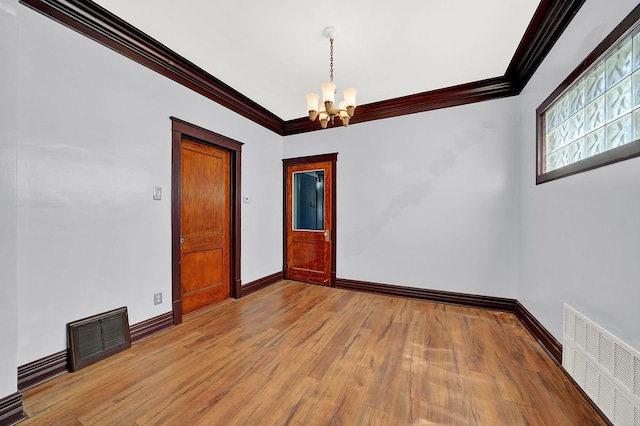 empty room with hardwood / wood-style floors, an inviting chandelier, and ornamental molding