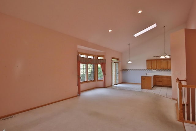 unfurnished living room featuring light carpet, a skylight, high vaulted ceiling, and a notable chandelier