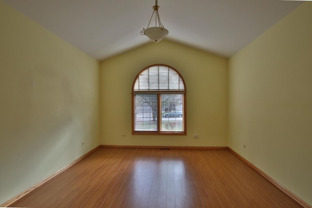 spare room featuring lofted ceiling and light hardwood / wood-style flooring