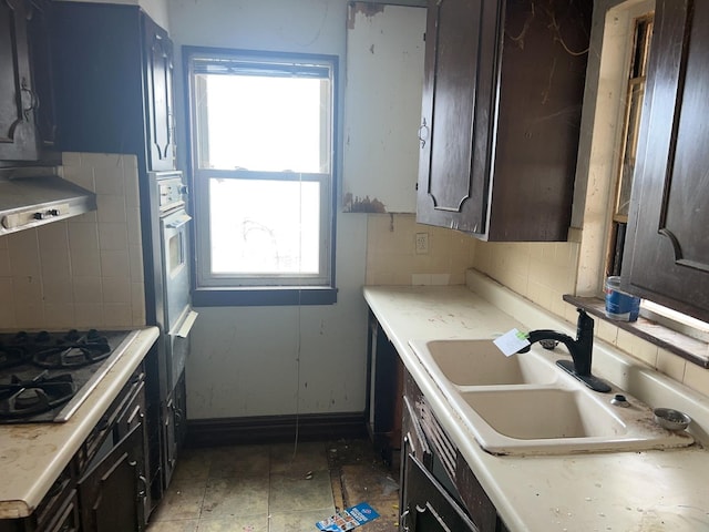 kitchen with sink, gas cooktop, backsplash, and dark brown cabinetry